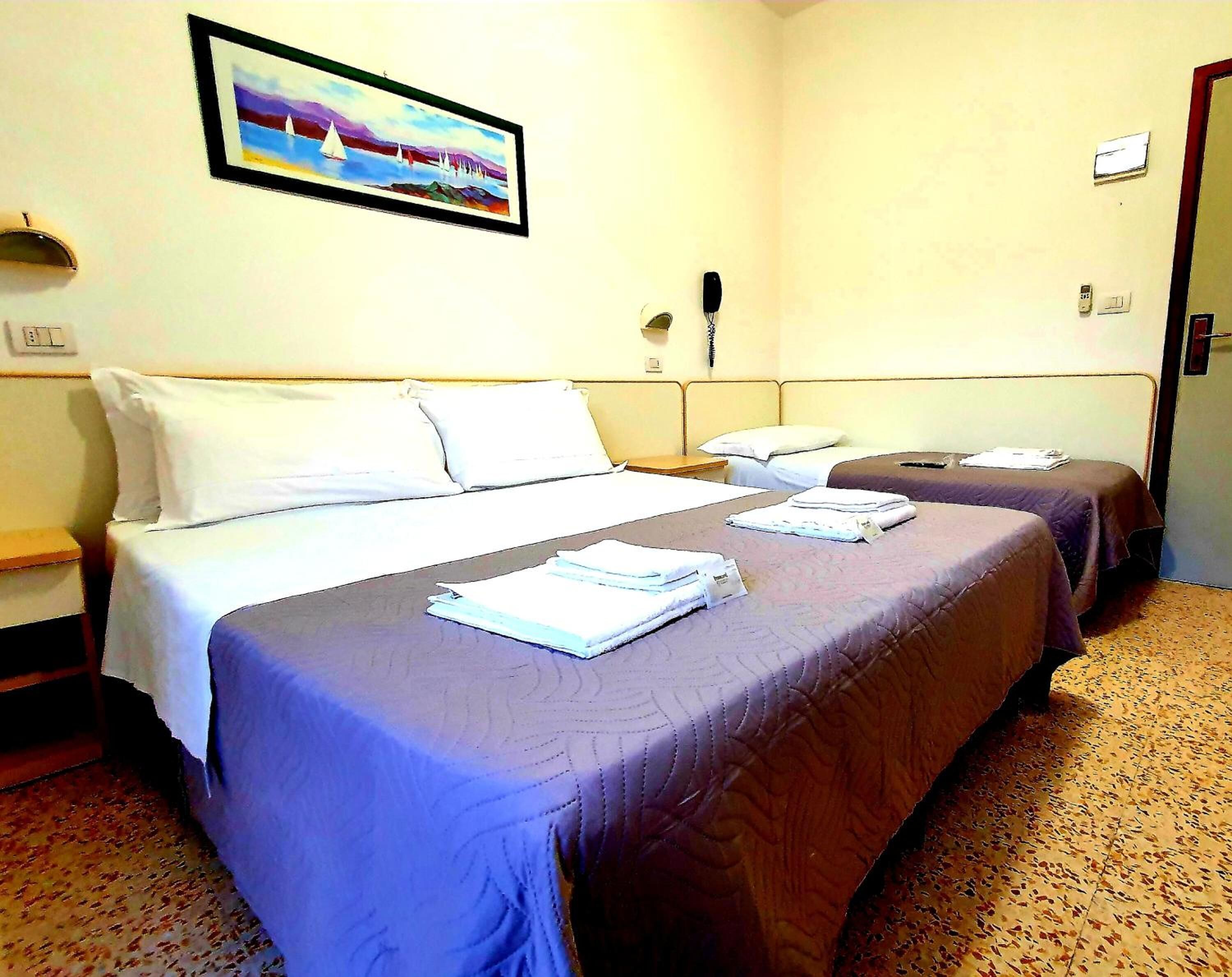 Ein Hotelzimmer mit zwei Betten, einem Bild an der Wand und einem Telefon.