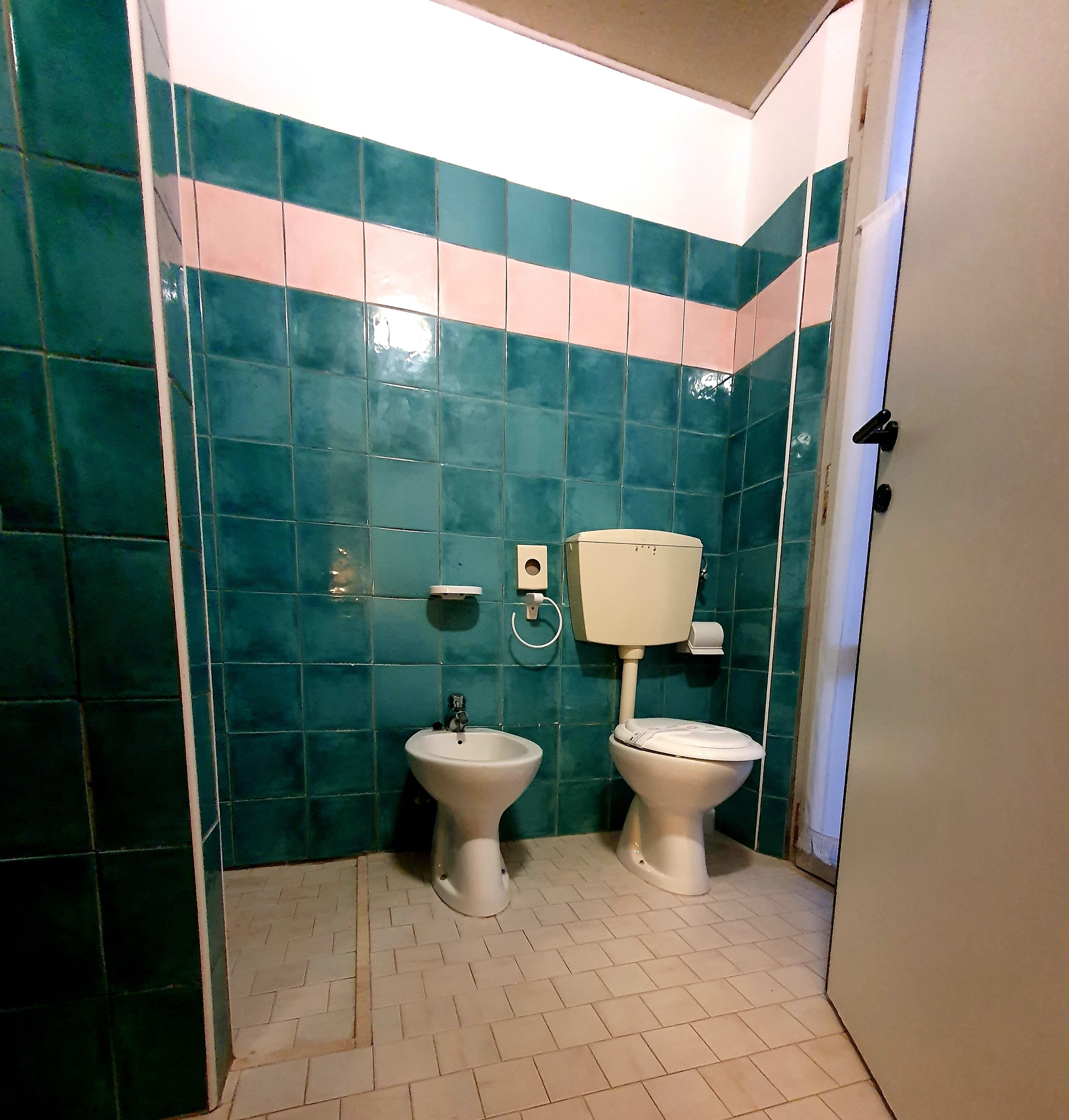 A bathroom with two toilets, a bidet, and a wall-mounted toilet paper holder.