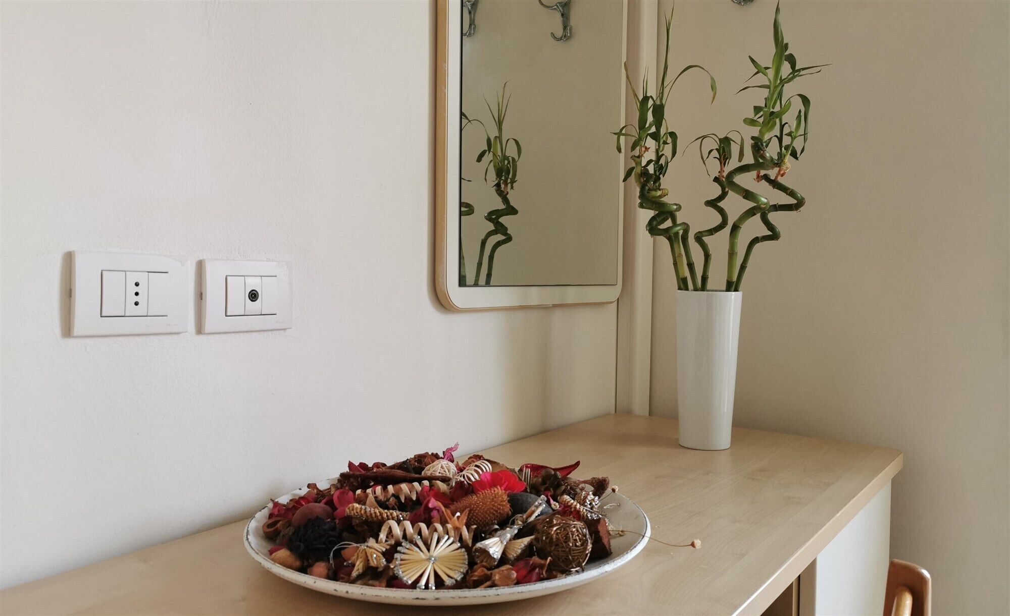 A room with a wooden desk, a bowl of decorative items, a mirror, and a potted plant.
