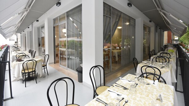 A restaurant with outdoor seating, large windows, and a modern design.