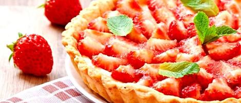Una tarta de fresas con hojas de menta sobre un plato blanco.