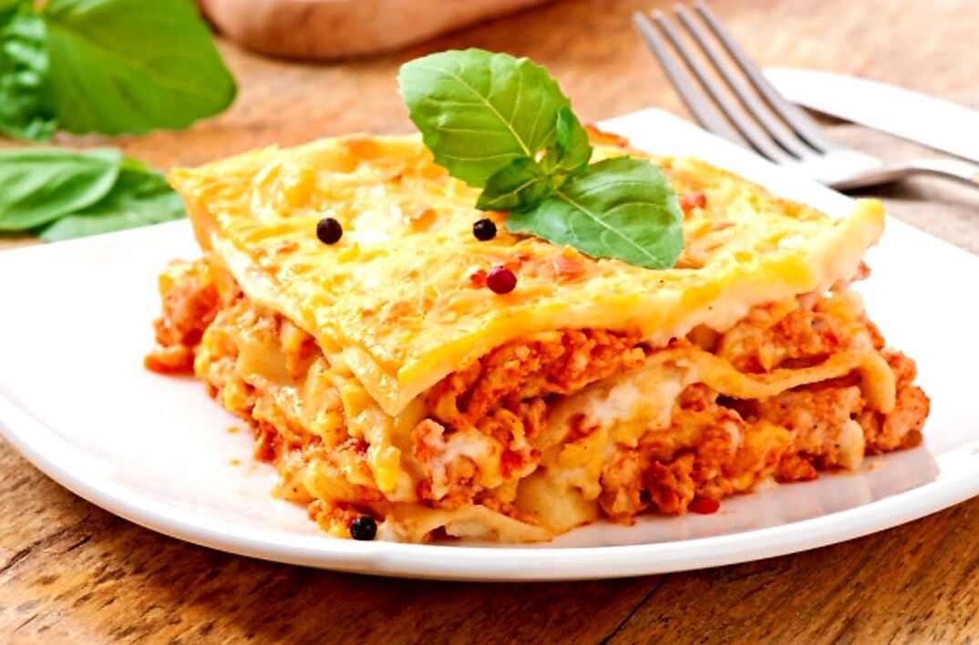 Une assiette de lasagnes, garnie d’une feuille de basilic.