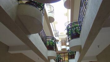 Un atrio de varios niveles con balcones, plantas en macetas y un espacio central abierto.
