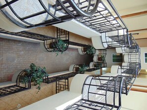 A spacious hotel lobby with multiple seating areas, a central staircase, and potted plants. - Upperhill View Hotel (Eldoret)