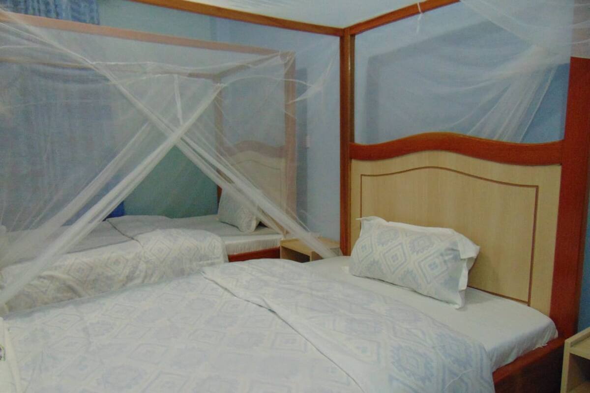Quarto com duas camas de solteiro, cada uma com cabeceira de madeira e roupa de cama branca.