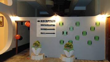 Un área de recepción con indicaciones hacia recepción, restaurante, habitaciones y salón.