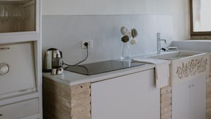 Una cocina con encimera de piedra, armarios blancos y una ventana sobre el fregadero.