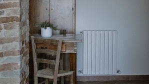 Una habitación rústica con un escritorio de madera, una silla, una planta en maceta y un radiador.
