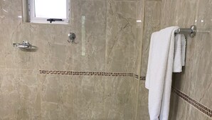 Un baño con inodoro, perchero para toallas y ventana.