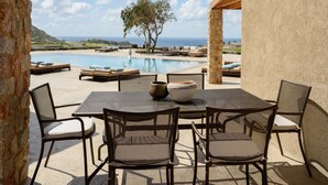 An outdoor patio with a pool, stone pillars, and a view of the sea. - Phaos at Cellaria Estate (Santorini)