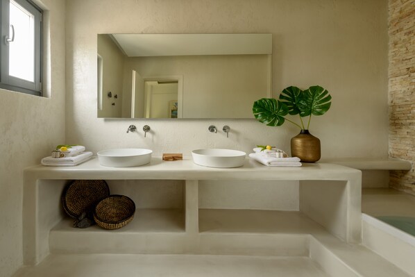 Une salle de bain moderne avec deux lavabos, un grand miroir et une plante en pot.