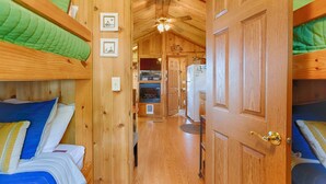 Un intérieur en bois avec des lits superposés, un ventilateur de plafond et un réfrigérateur.