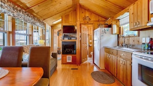 Un intérieur de chalet chaleureux comprenant un coin repas, une cuisine et une cheminée.