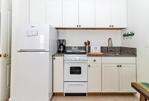 Une cuisine avec un réfrigérateur blanc, une cuisinière et une machine à café.