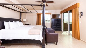 Un dormitorio amplio con una cama grande, un ventilador de techo, un armario y vistas a través de un cristalero corredizo.
