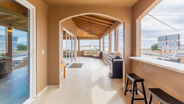 Un espacio al aire libre techado con una parrilla, asientos y vistas de la ciudad.