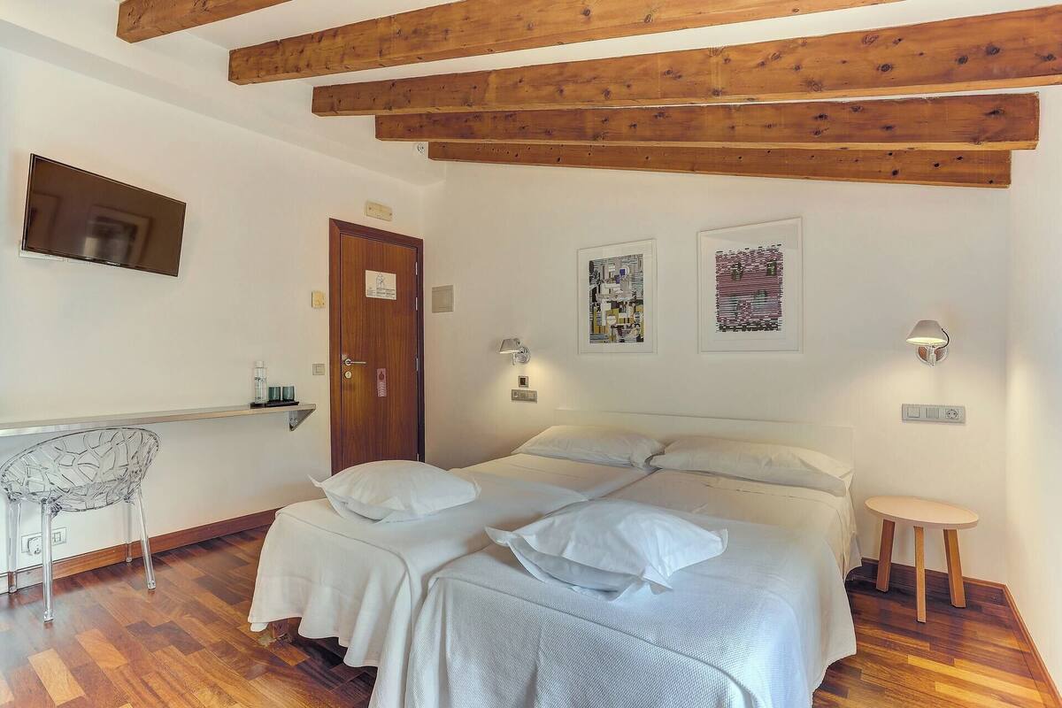 Une chambre à coucher avec un lit, un plafond en bois, un téléviseur fixé au mur et des œuvres d’art.