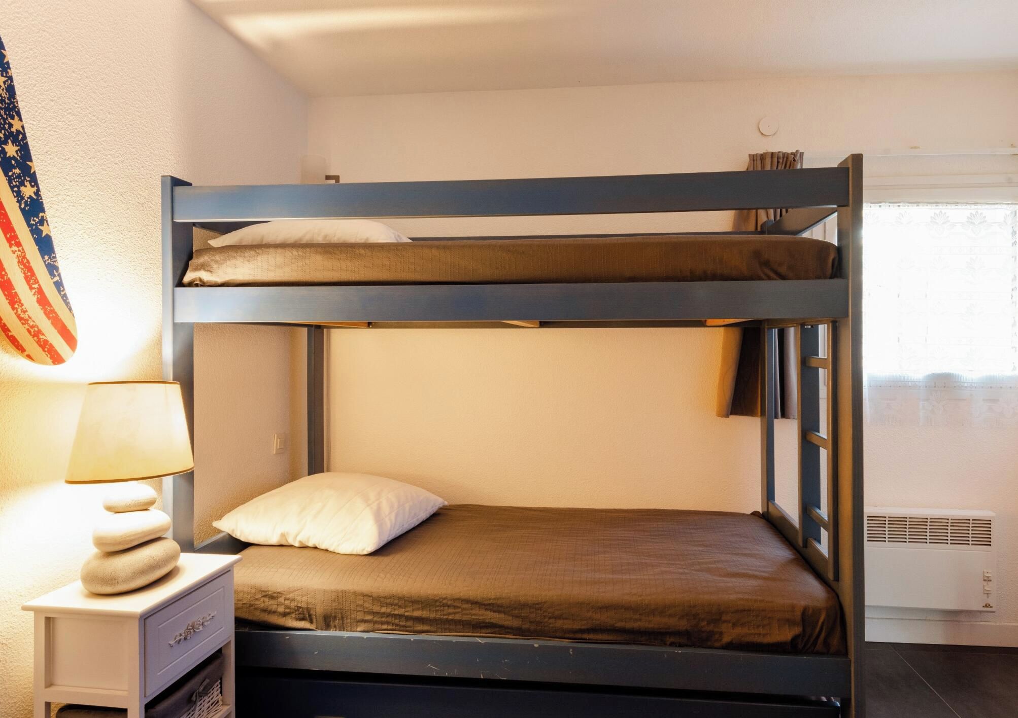 Un lit superposé avec un oreiller et une lampe sur une table de chevet.