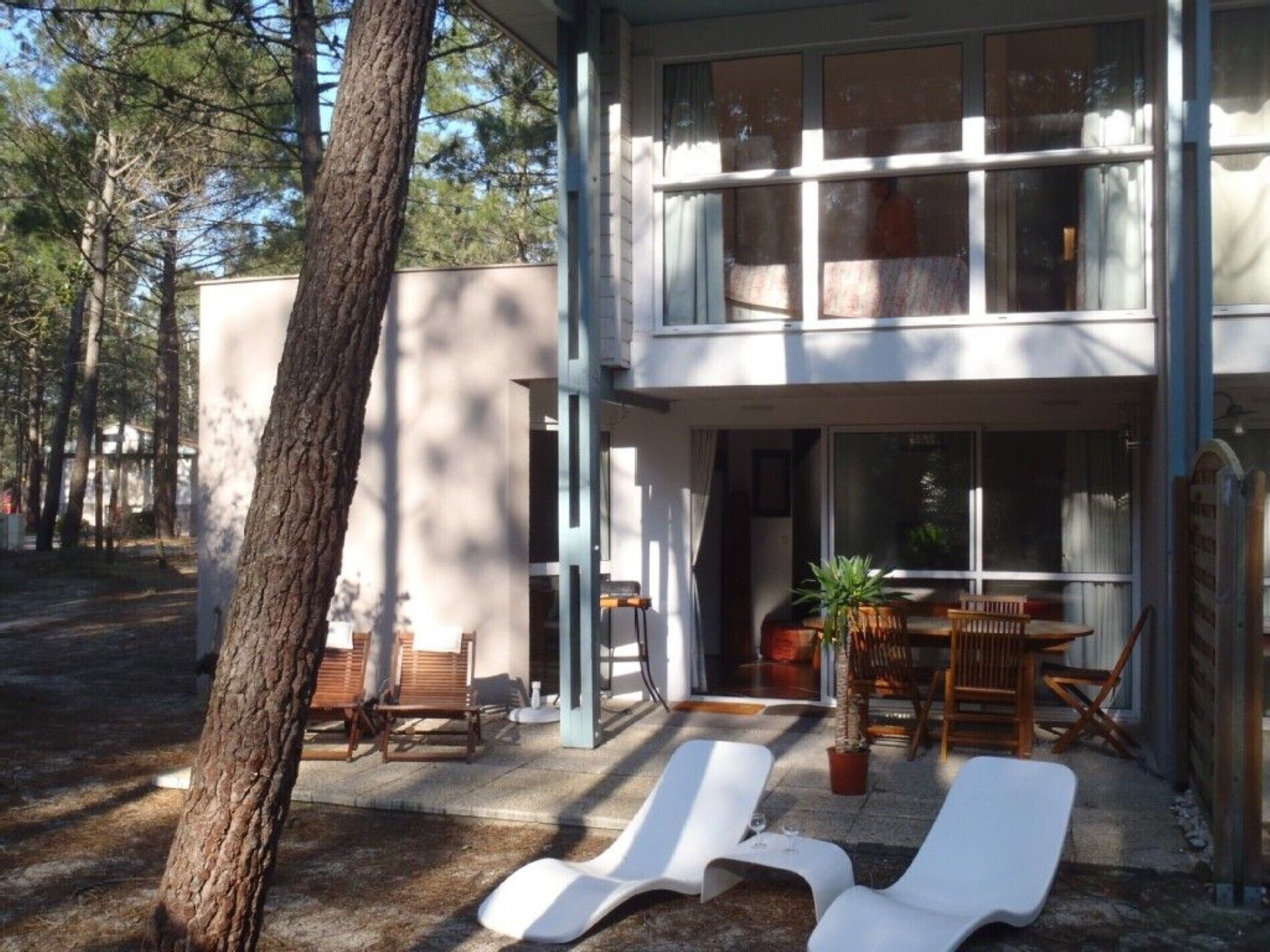 A two-story building with a patio area featuring lounge chairs and a dining table.