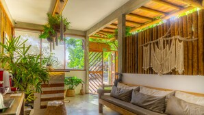 A cozy room with a wooden bench, potted plants, and a macrame wall hanging. - Casa Valentini Pousada (Jijoca de Jericoacoara)