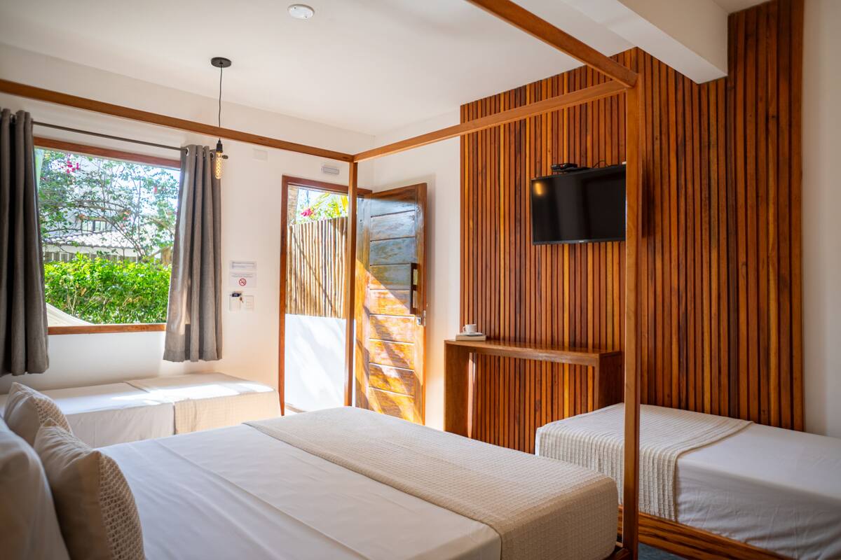 Une chambre avec deux lits, un téléviseur fixé au mur et une fenêtre avec des rideaux.
