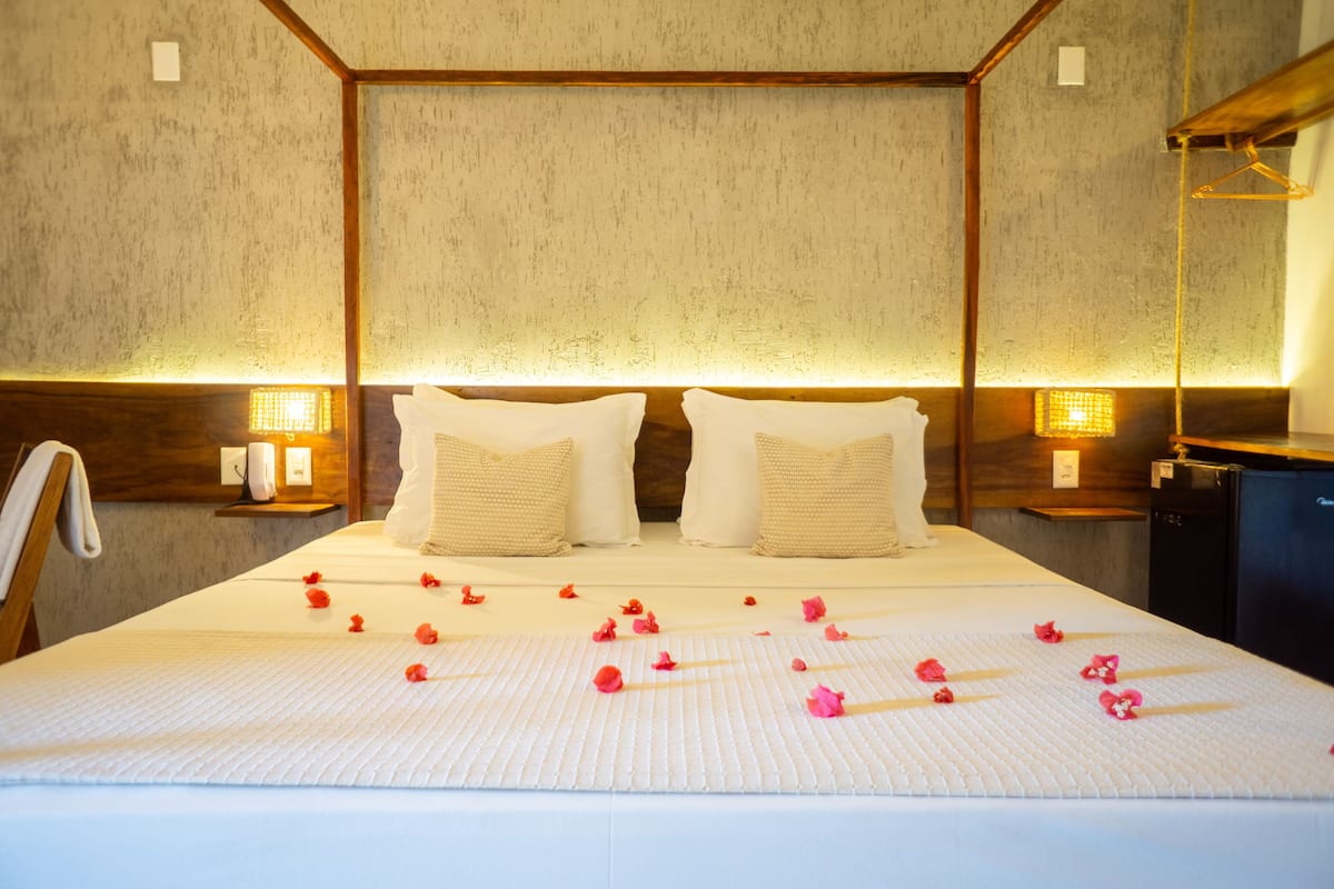 Un lit bien fait, décoré de pétales de rose, avec une tête de lit en bois et des lampes de chevet.