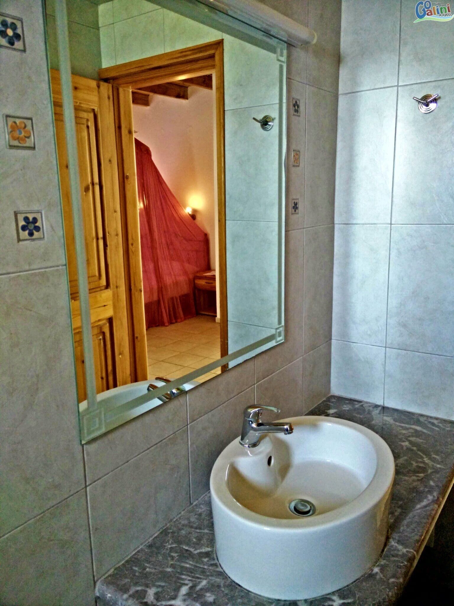 A bathroom with a large mirror, a sink, and a shower area.