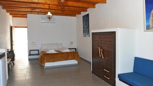 Ein Schlafzimmer mit einem Bett, einem Kleiderschrank, einem blauen Sofa und einer Holzbalkendecke.