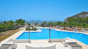Ein Schwimmbecken mit Liegestühlen und Blick aufs Meer.