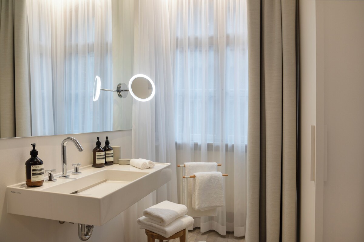 A modern bathroom with a large mirror, a sink, and a towel rack.