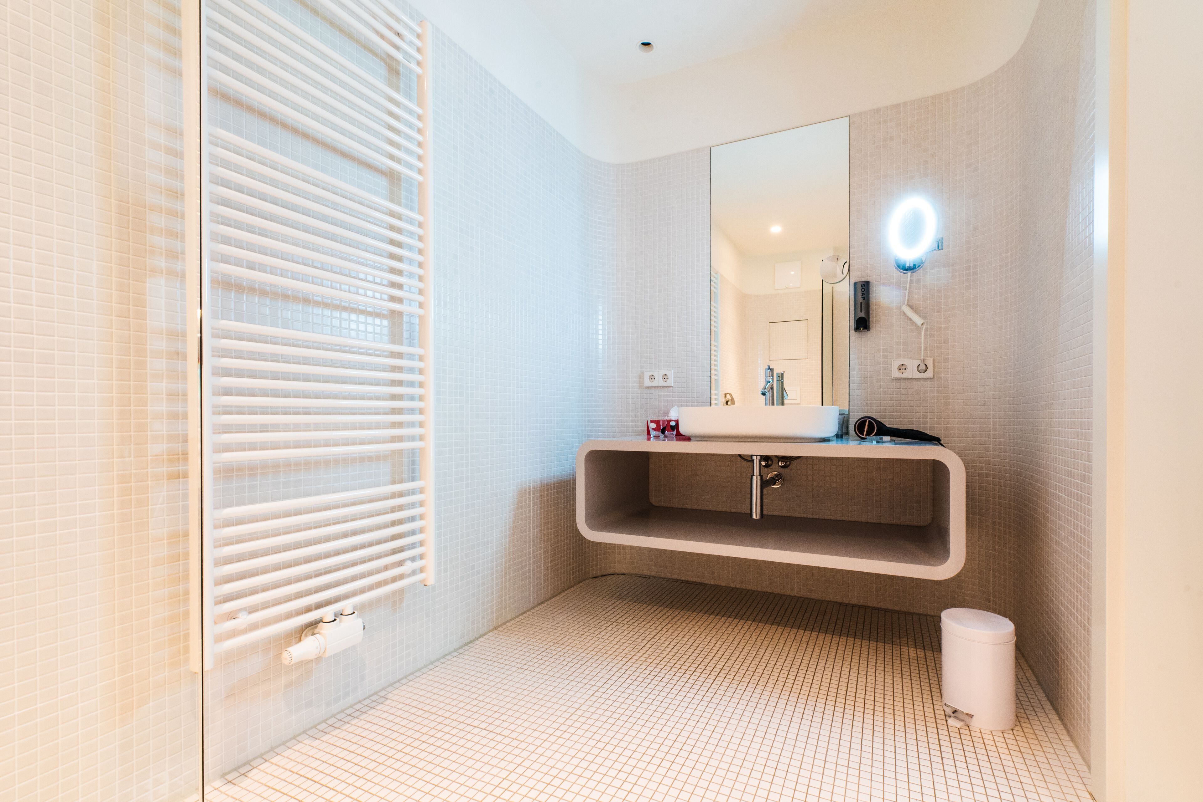 Un baño moderno con un espejo grande, un lavamanos empotrado y suelo con calefacción.