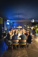A group of people seated around a table in a modern, well-lit indoor space with wooden flooring and a ceiling with a unique pattern.