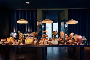 A buffet table with various food items and a kitchen in the background.