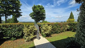 Un sendero de jardín que conduce a un pabellón, rodeado de setos y árboles bien cuidados.