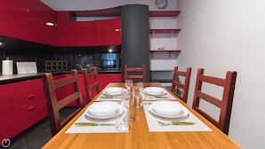 A dining area with a wooden table set for four, red cabinets, a black column, and a clock on the wall. - Italianway - Massarani 5 (Milan)