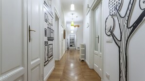 A hallway with white walls, wooden flooring, and doors with black and white artwork. There are pendant lights and a radiator on the wall. - Italianway - Piero Della Francesca 84 (Milan)
