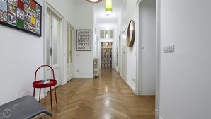 A hallway with a wooden floor, a red chair, a radiator, and a framed alphabet art piece. - Italianway - Piero Della Francesca 84 (Milan)