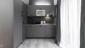 Une cuisine moderne avec des meubles gris, un four encastré et une machine à café.