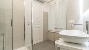 A modern bathroom with a glass shower enclosure, a white sink, and a large mirror. - Italianway - Garibaldi 104 A (Milan)