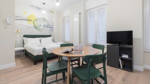 A hotel room with a bed, a table with chairs, a television, and a bookshelf. - Italianway - Garibaldi 104 A (Milan)