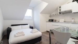A modern bedroom with a bed, a glass table, and a kitchenette. - Italianway - Corso Como 9 (Milan)