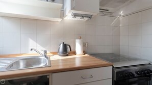 Una cocina moderna con un lavamanos de acero inoxidable, hervidor y estufa.