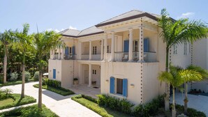 A two-story building with a balcony, columns, and a covered patio area. - Luxury Golf View Villa in Punta Cana Resort & Club with Private Pool and Jacuzzi (Punta Cana)
