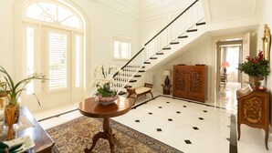 A spacious foyer with a high ceiling, a grand staircase, and a large wooden cabinet. - Luxury Golf View Villa in Punta Cana Resort & Club with Private Pool and Jacuzzi (Punta Cana)