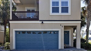 Ein zweigeschossiges Haus mit Garage, Balkon und kleiner Veranda.