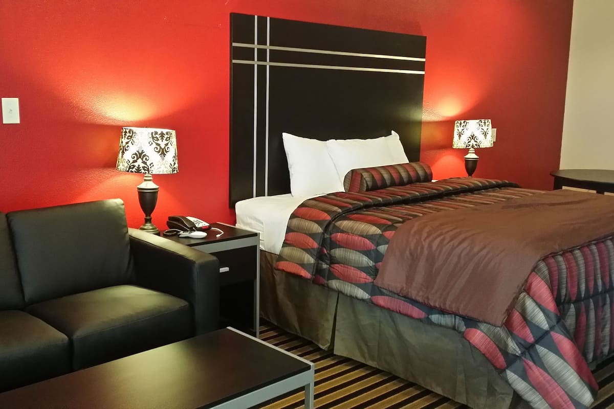 Une chambre d’hôtel comprenant un lit, un canapé, une table de chevet avec une lampe et un téléphone.