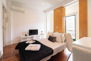 A modern hotel room with a bed, a TV, a wooden accent wall, and a balcony view.