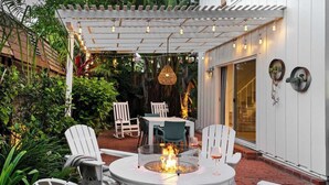 Une terrasse avec une table ronde, des chaises et un foyer.