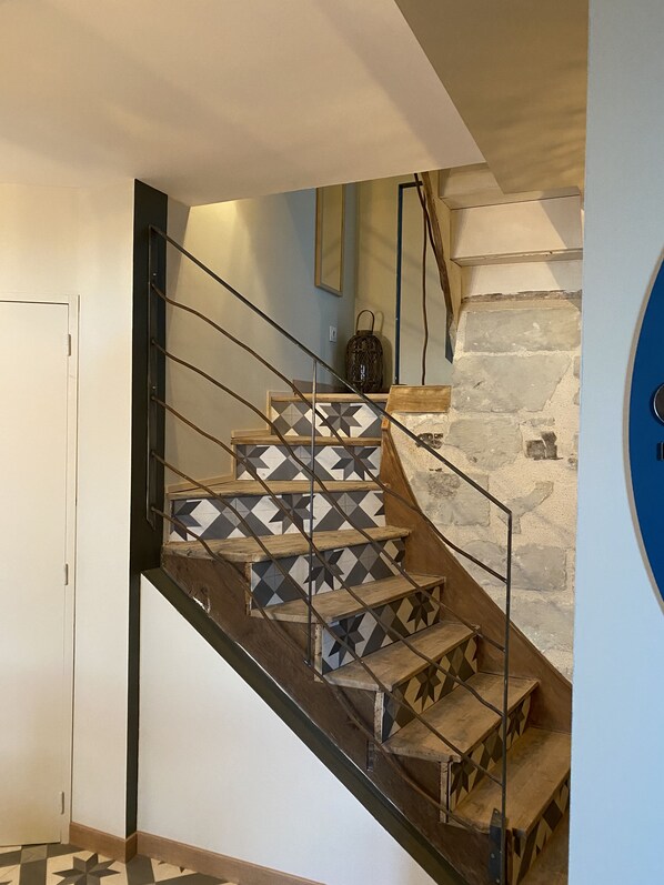 A staircase with geometric patterned tiles, a stone wall, and a metal railing. - View over the Loire. Le Futreau, gîte 8/9 pers (Chalonnes-sur-Loire)