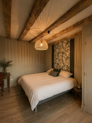 A bedroom with a large bed, wooden beams on the ceiling, a textured wall, and a hanging light fixture.